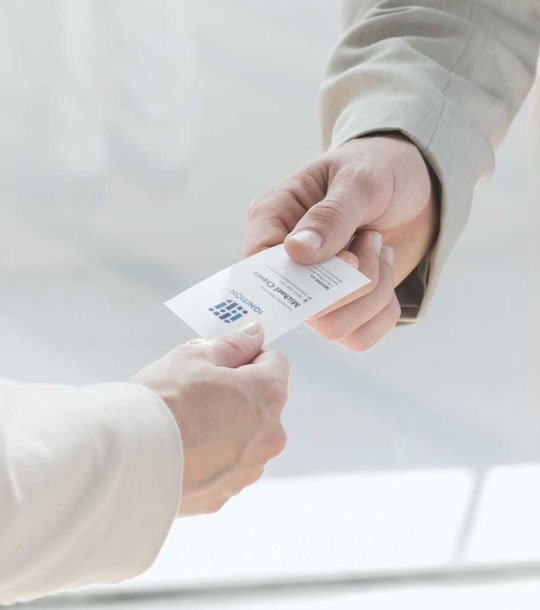 Handing over a business card designed by TMCreation during a professional introduction with an additional blue business card shown as an example of print quality