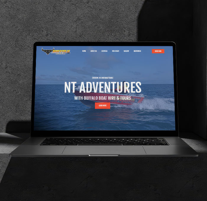 Website design displayed on a laptop set against a dark stone textured background with bold contrast and deep colours