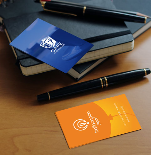 Two business card designs placed on a desk with a pen, showing clean branding work