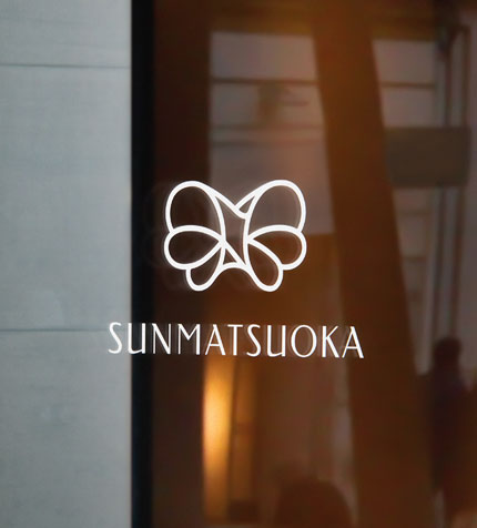 Sunmatsuoka logo applied as white signage on a glass door, designed by TMCreation
